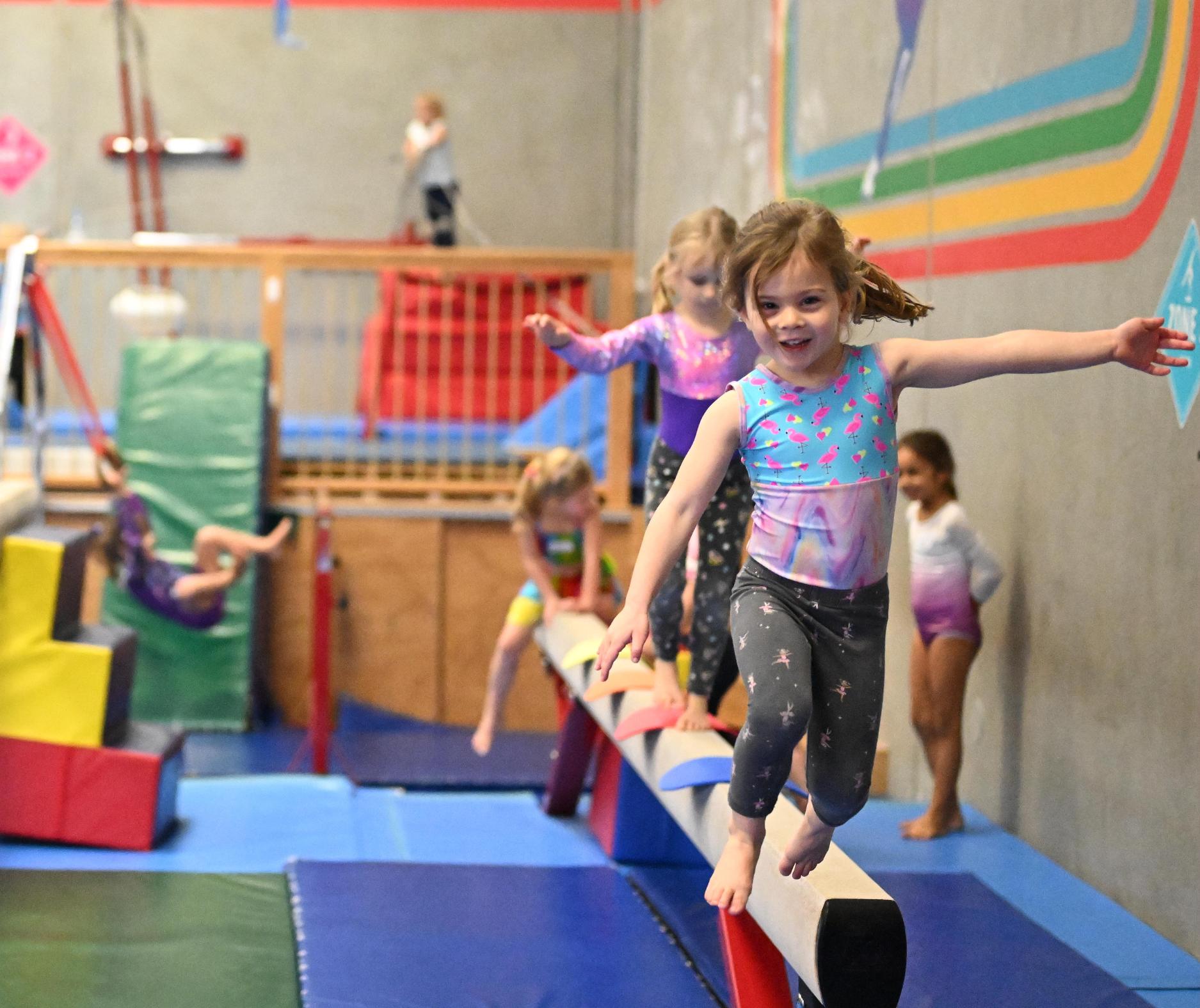 Pre-schoolers having fun and learning balance skills on the bar at gymnastics