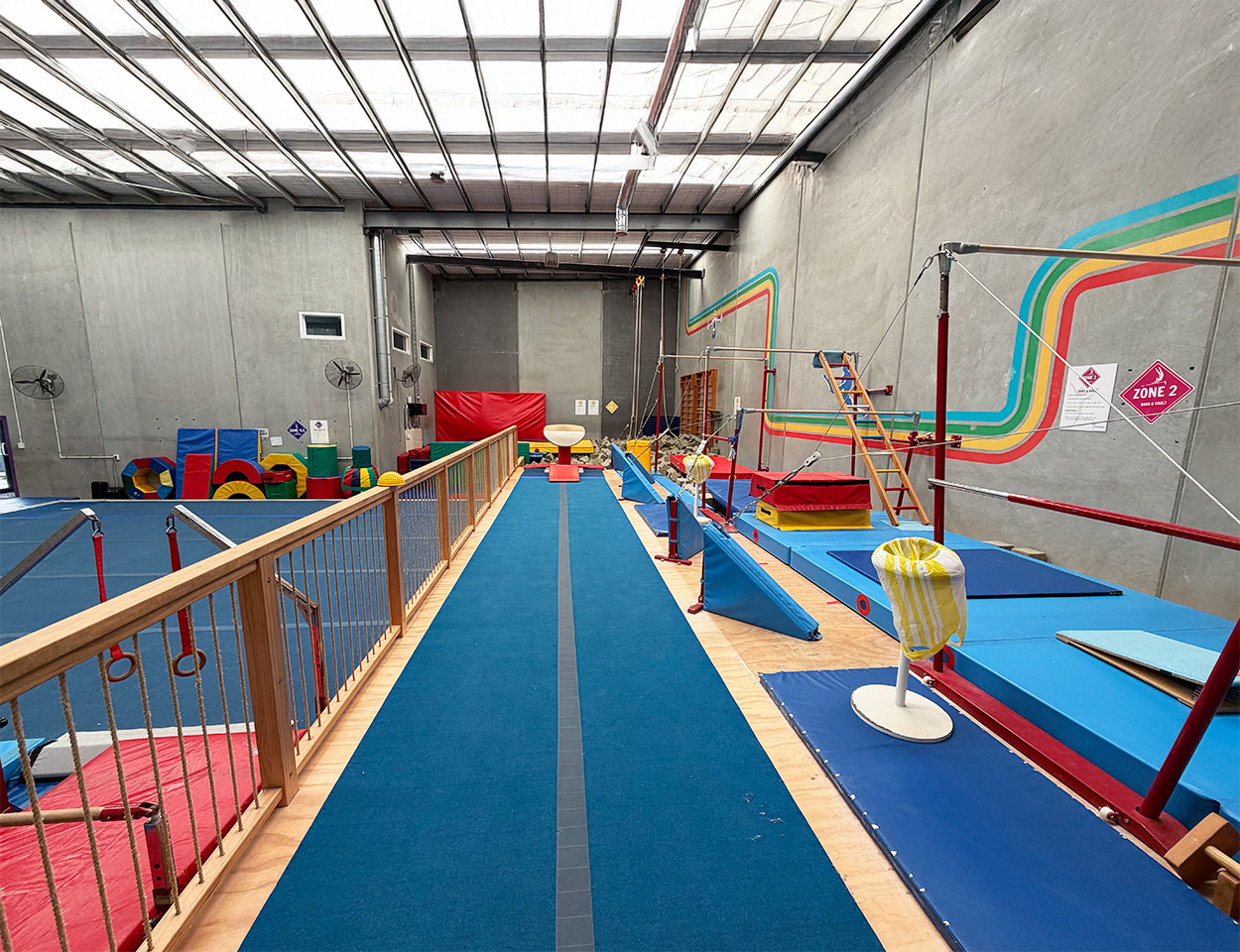 Interior of Xpression's Gymnastics in Hobsonville looking down the vault lane with high bars to the right, and gymnastics floor to the left