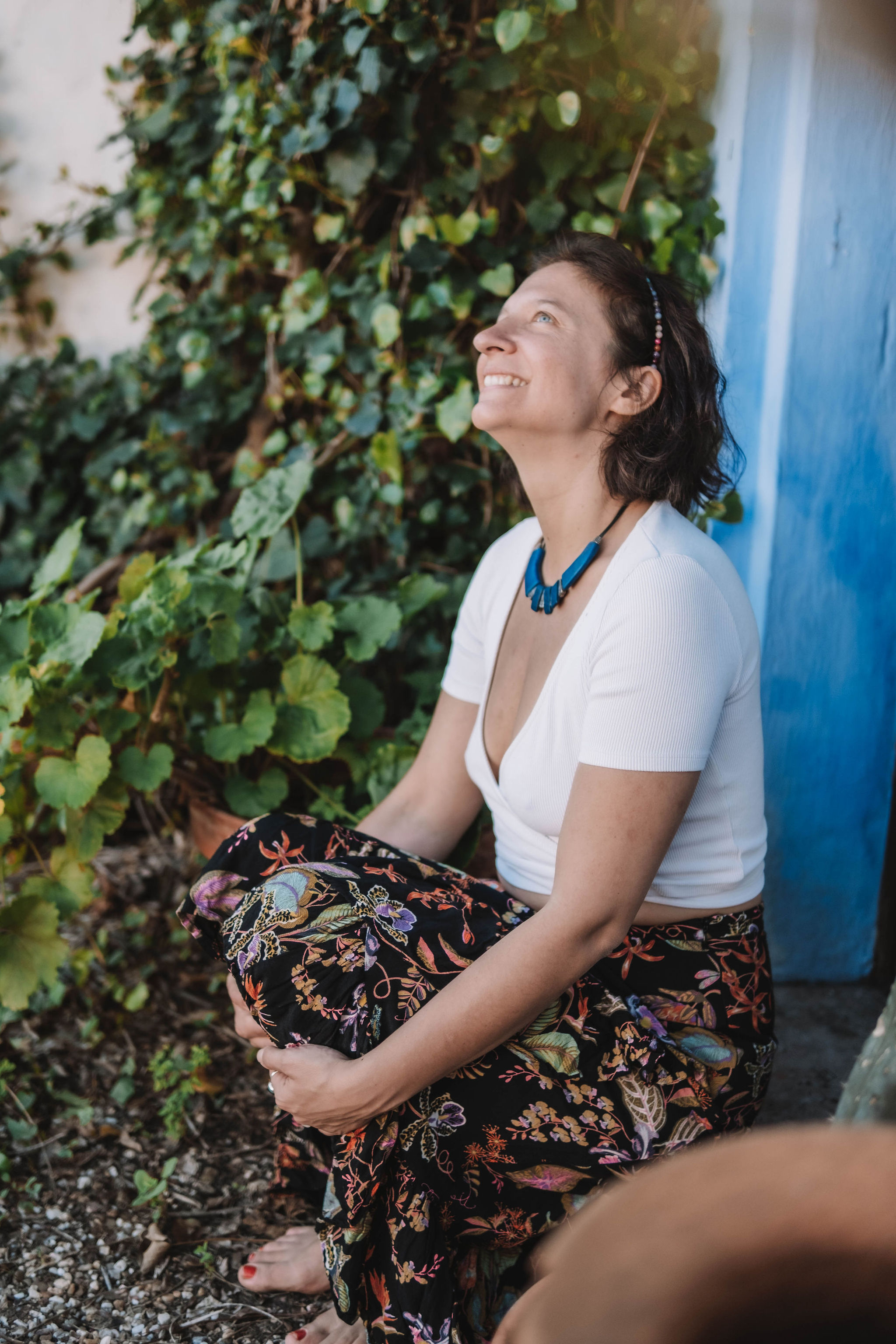 Two women sitting outdoors at night near a fire, one wearing a patterned sweater and the other wrapped in a shawl.