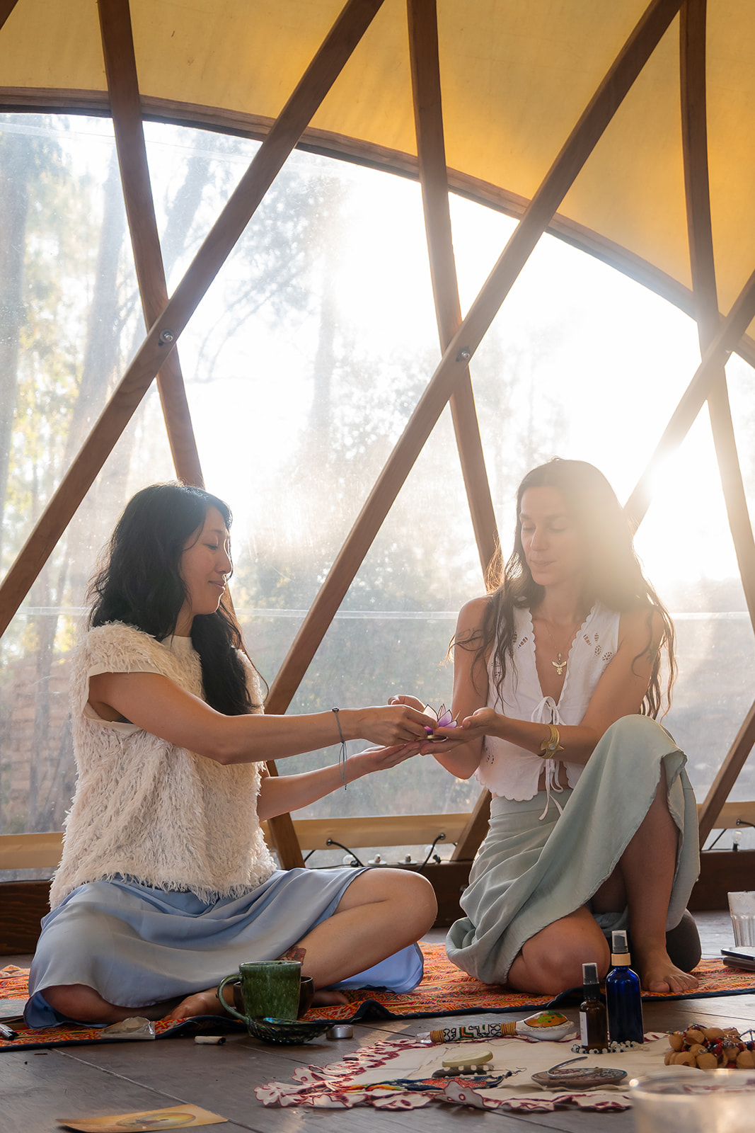 Three women outdoors enjoying a sunny day, appearing joyful and expressive with raised arms and closed eyes under clear blue sky.