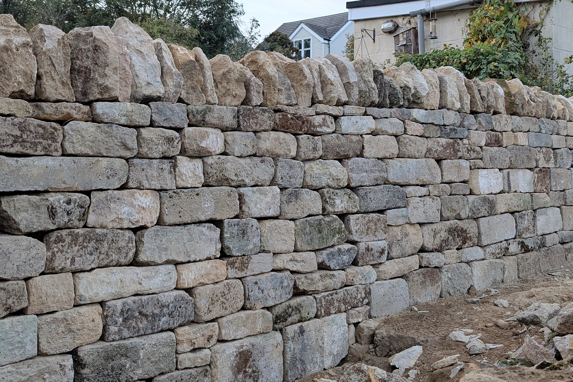 A dry stone wall constructed from chiseled face reclaimed limestone in Weldon, Northamptonshire