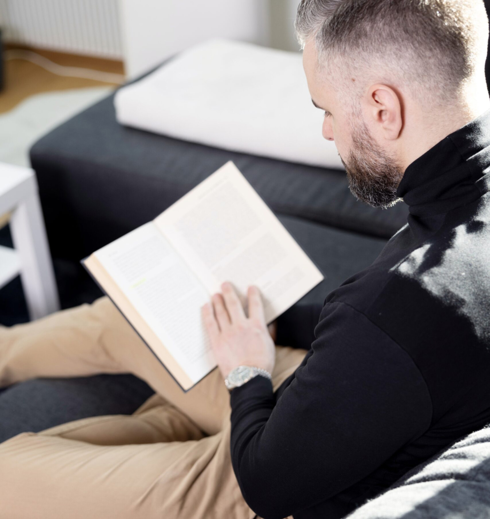 Henrik Telepski sitzt auf dem Sofa und liest im Buch Steuersparmodelle für Schweizer Unternehmen.