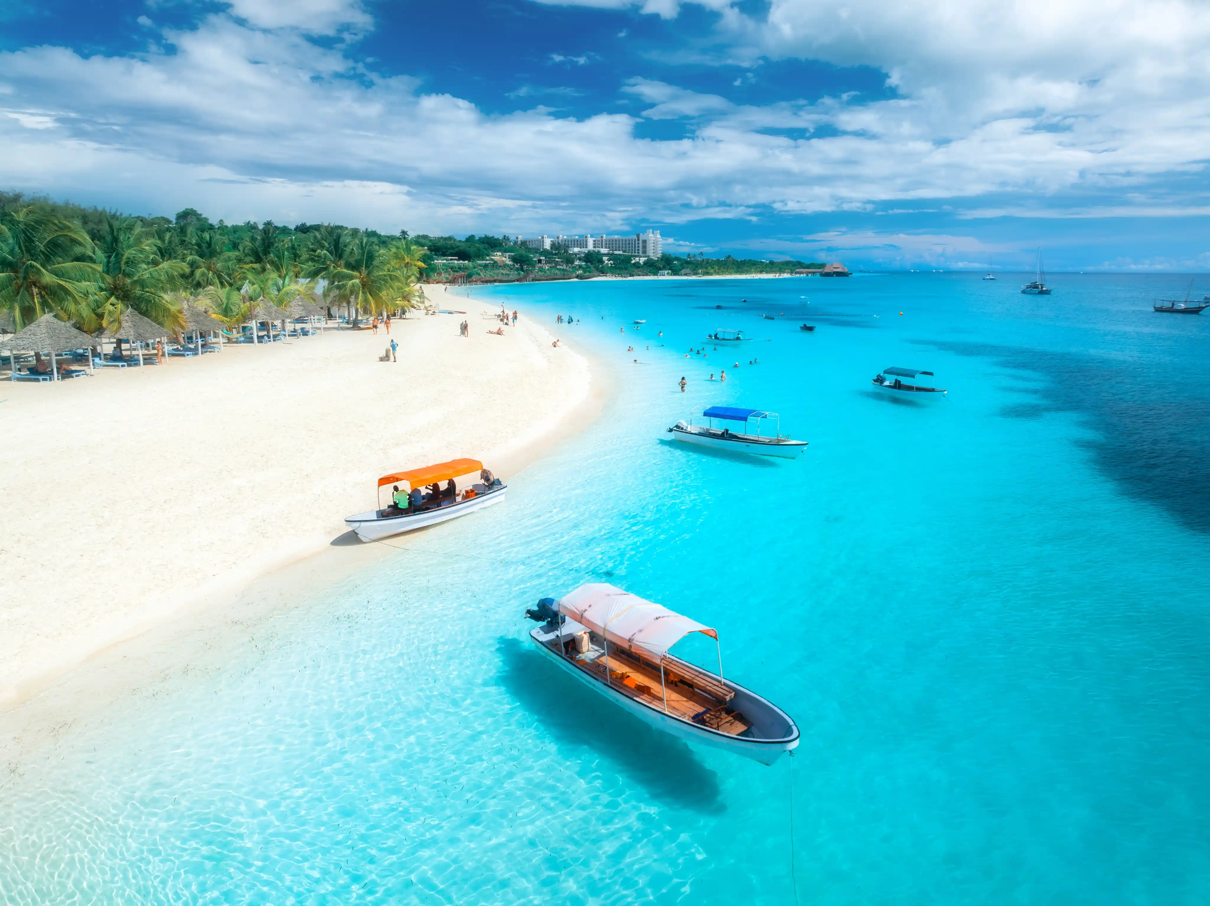 Aerial view of boats on turquoise water near white sand beach