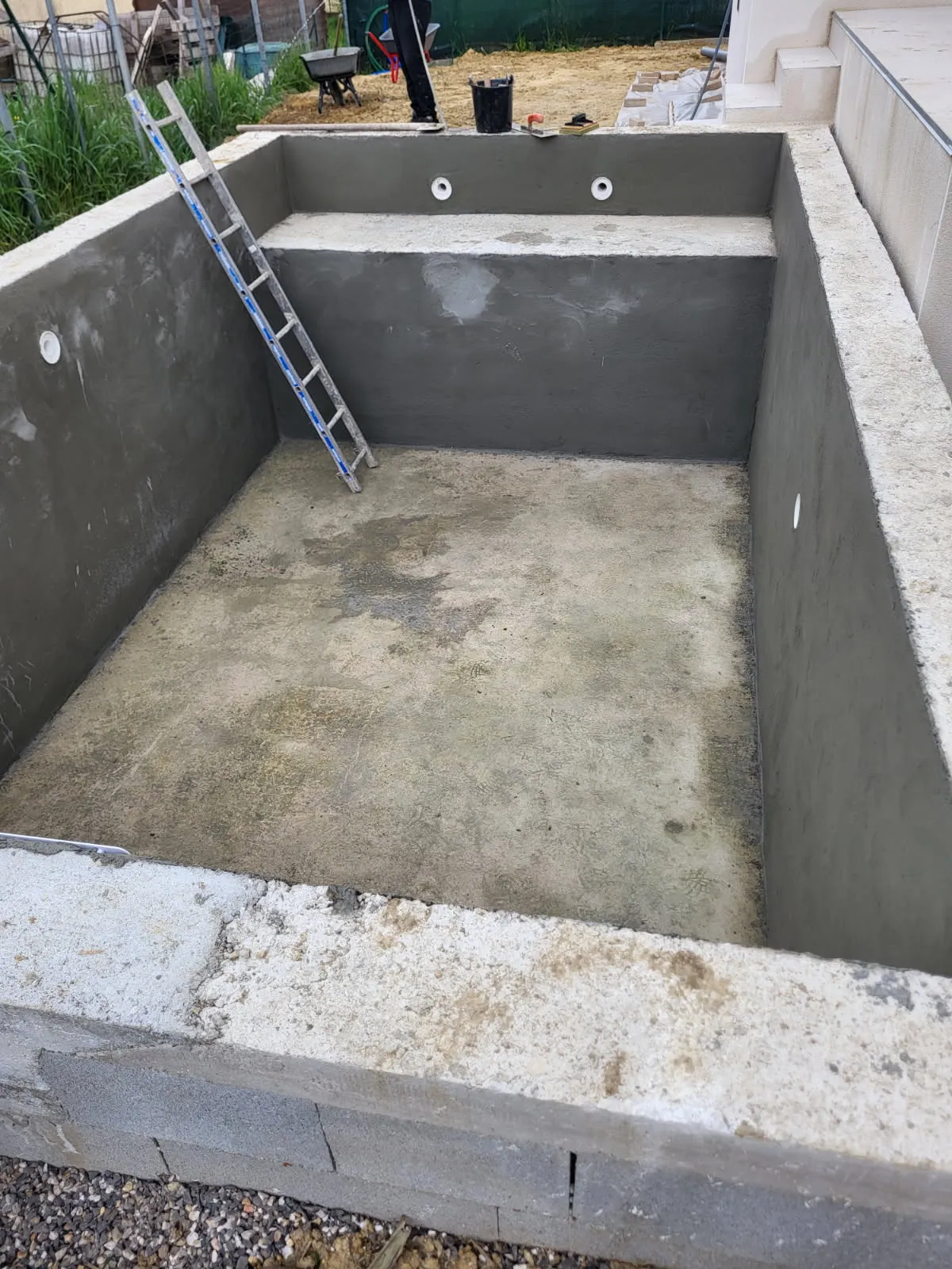 Piscine en béton enduite avec banquette et buses de refoulement, avant revêtement