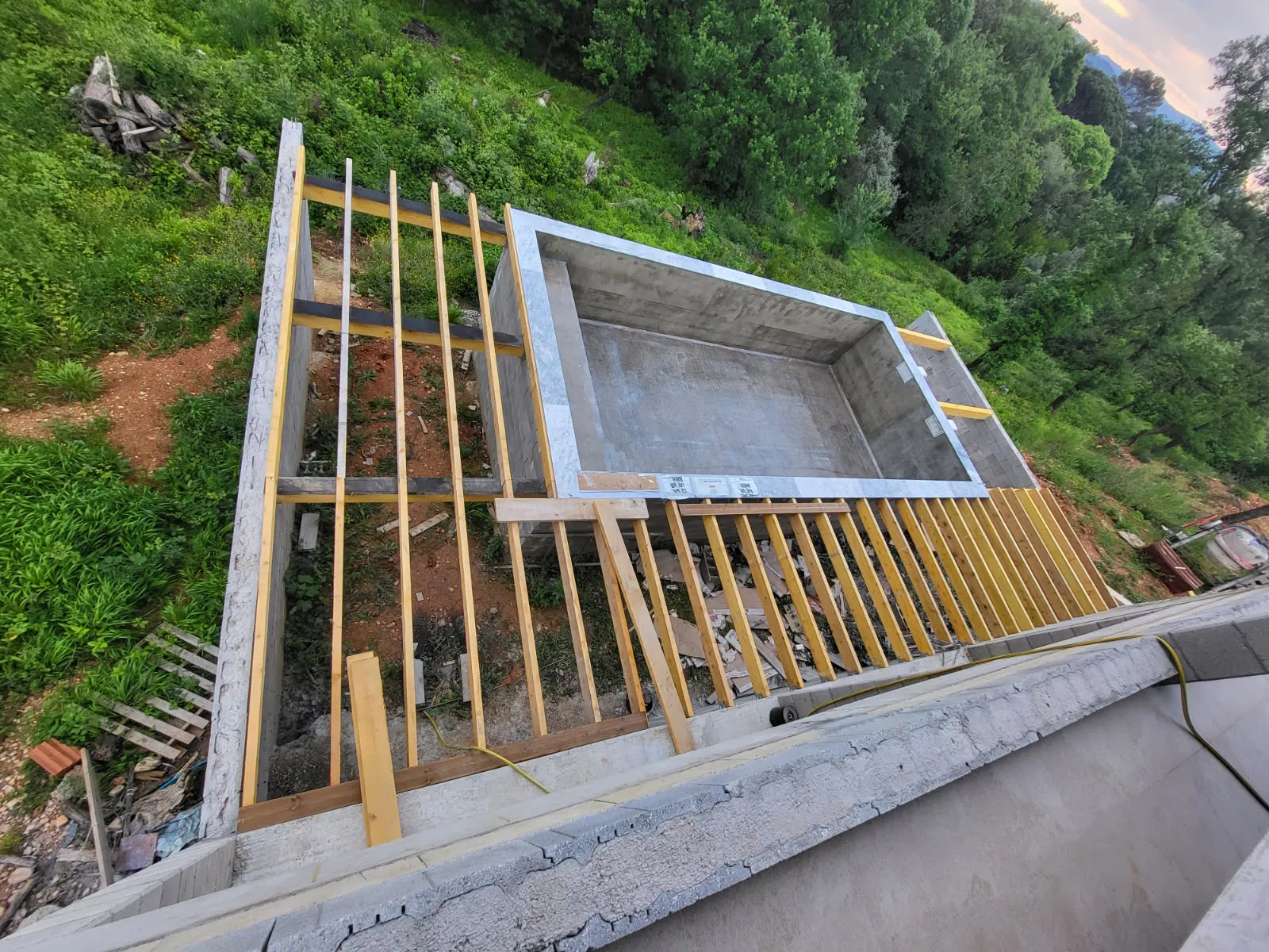 Bassin de piscine en béton construit sur un terrain en pente, vue de dessus