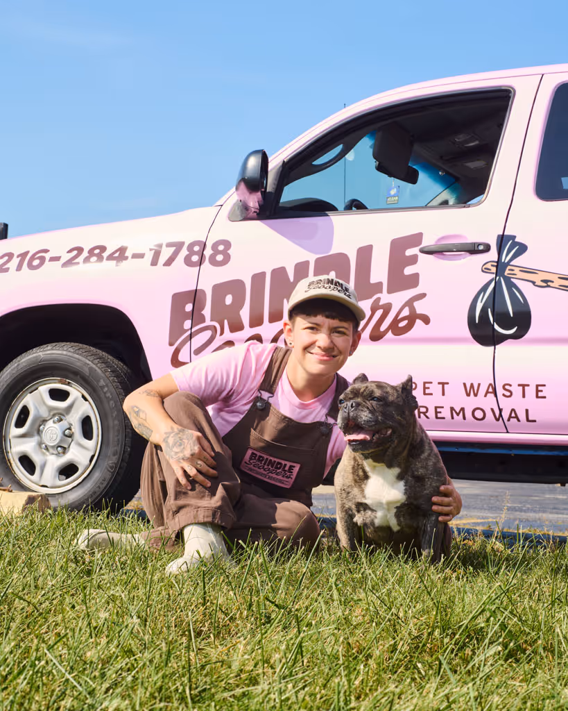 Brindle Scooper technician, holding our Frenchie mascot, in front of our pink truck.