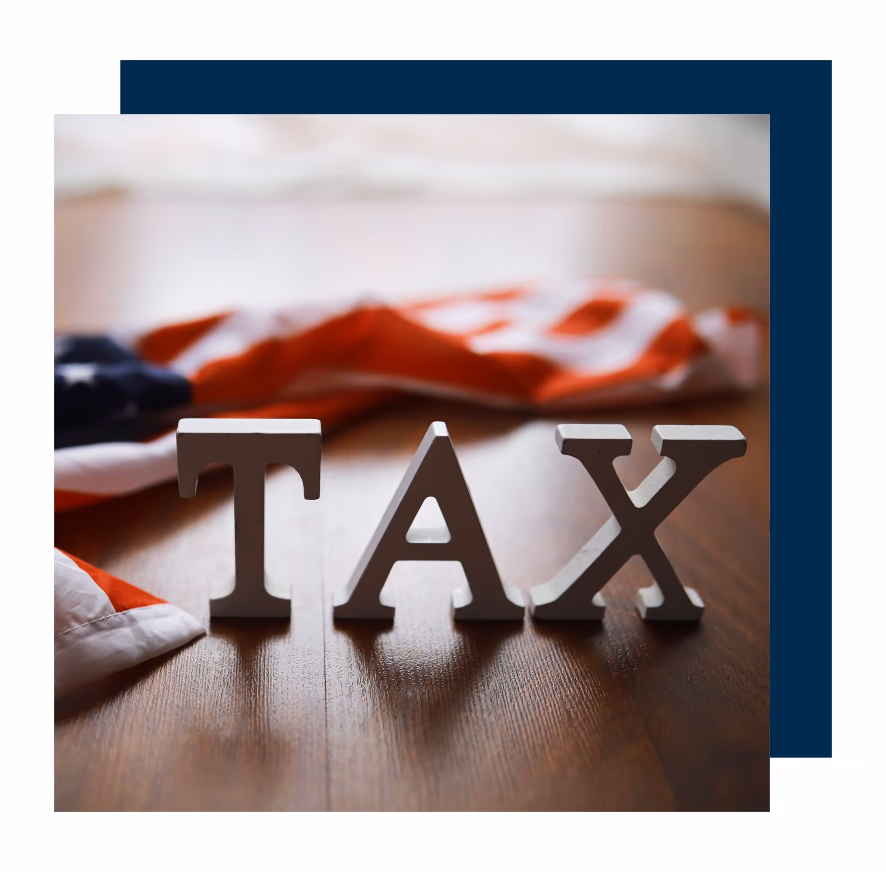Wooden letters spelling “TAX” displayed in front of an American flag