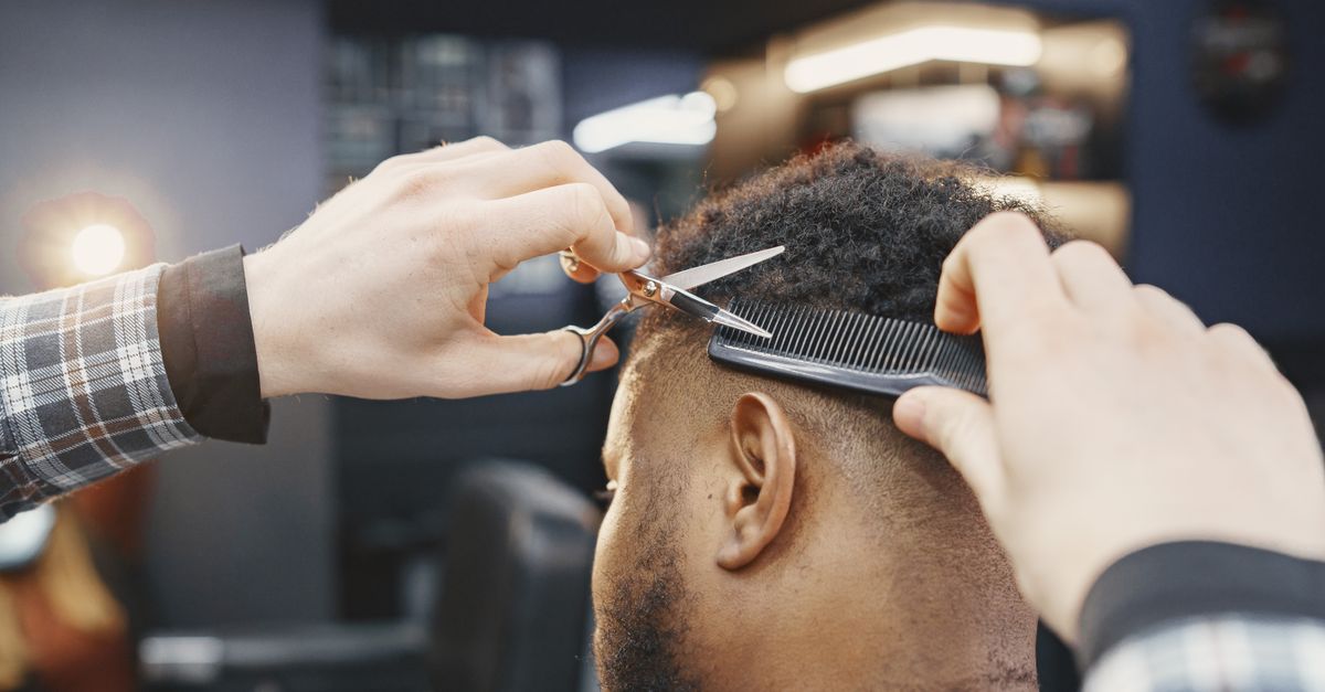 Close-up of a barber giving a haircut with scissors and comb in a modern salon.