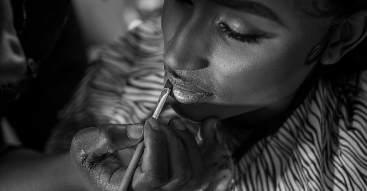 A close-up black and white photo of a woman applying makeup in Jos, Nigeria.