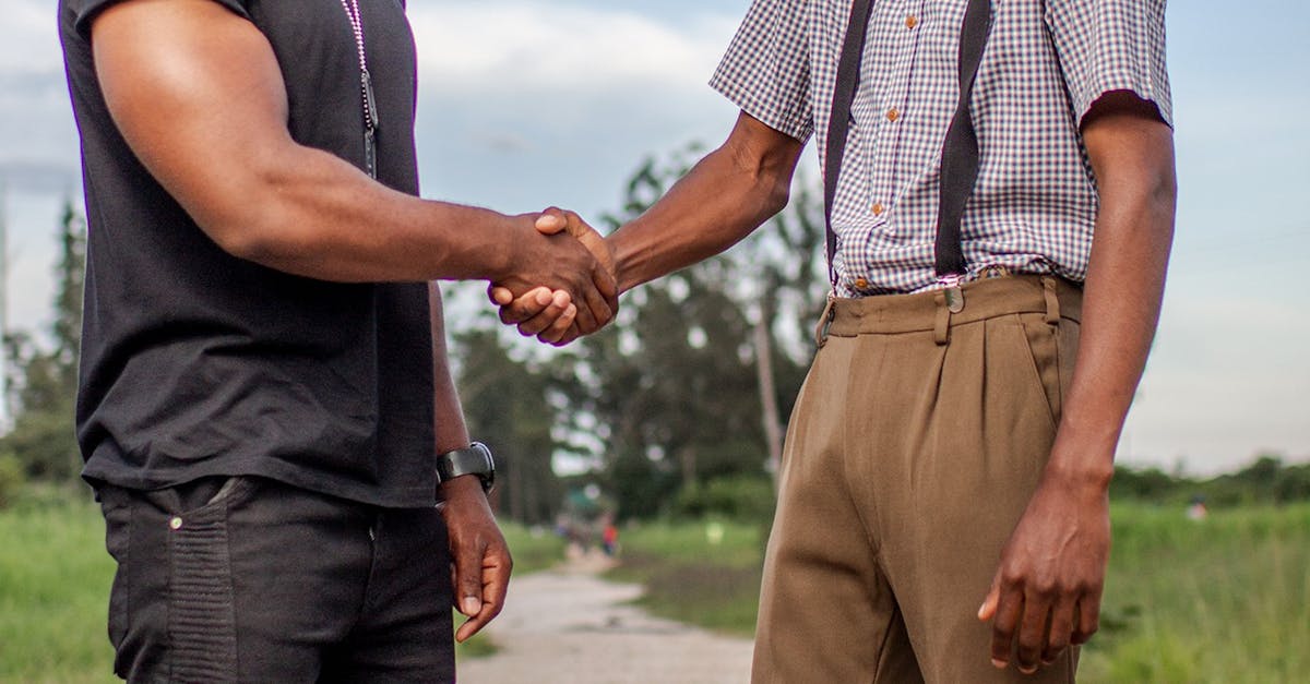 Two men shaking hands outdoors in Lusaka, Zambia. Captures cooperation and agreement.