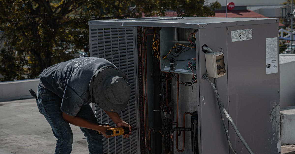 A technician is repairing an air conditioning unit on a rooftop, demonstrating skilled manual work.