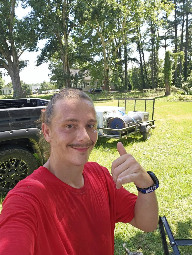 Steven posing with his truck and trailer behind him. 