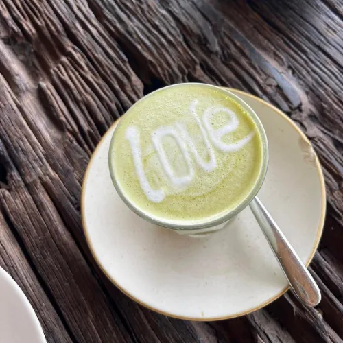 Matcha latte with the word love written in the foam, on a weathered wood table