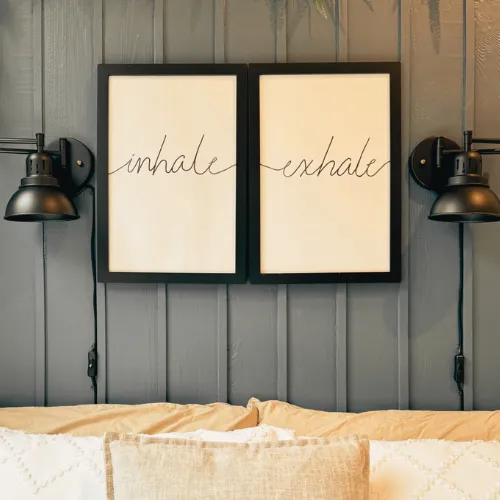 Framed inhale and exhale prints on a panelled wall above a bed