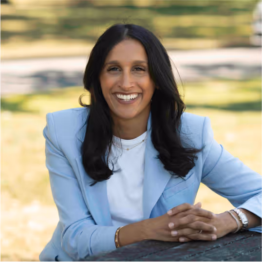 Tina Sadarangani sitting on a bench smiling. 