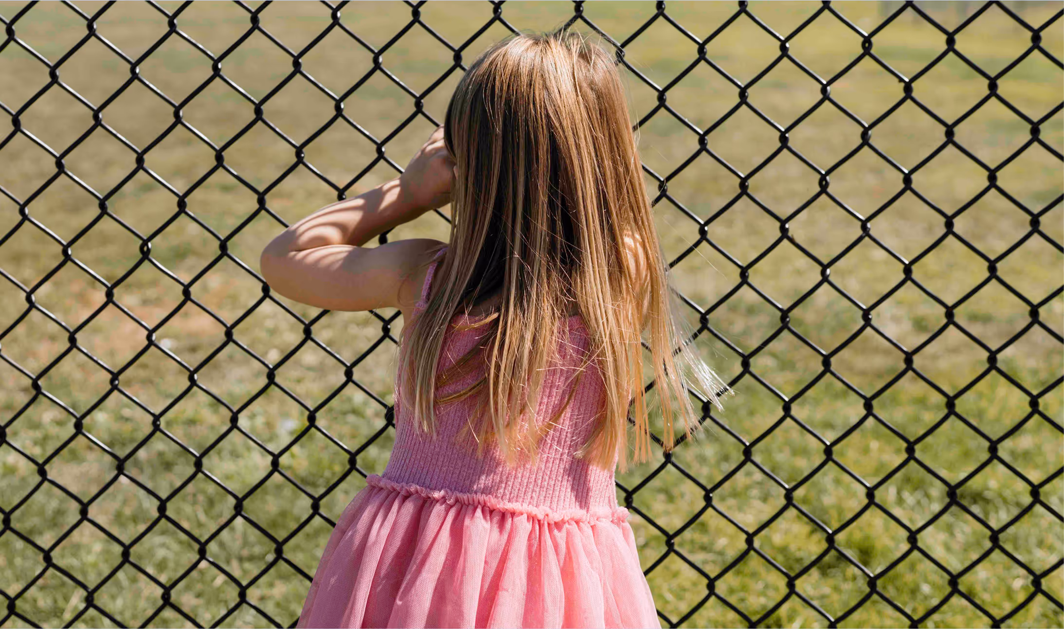 A young girl peaking through Hommocks Field fence.