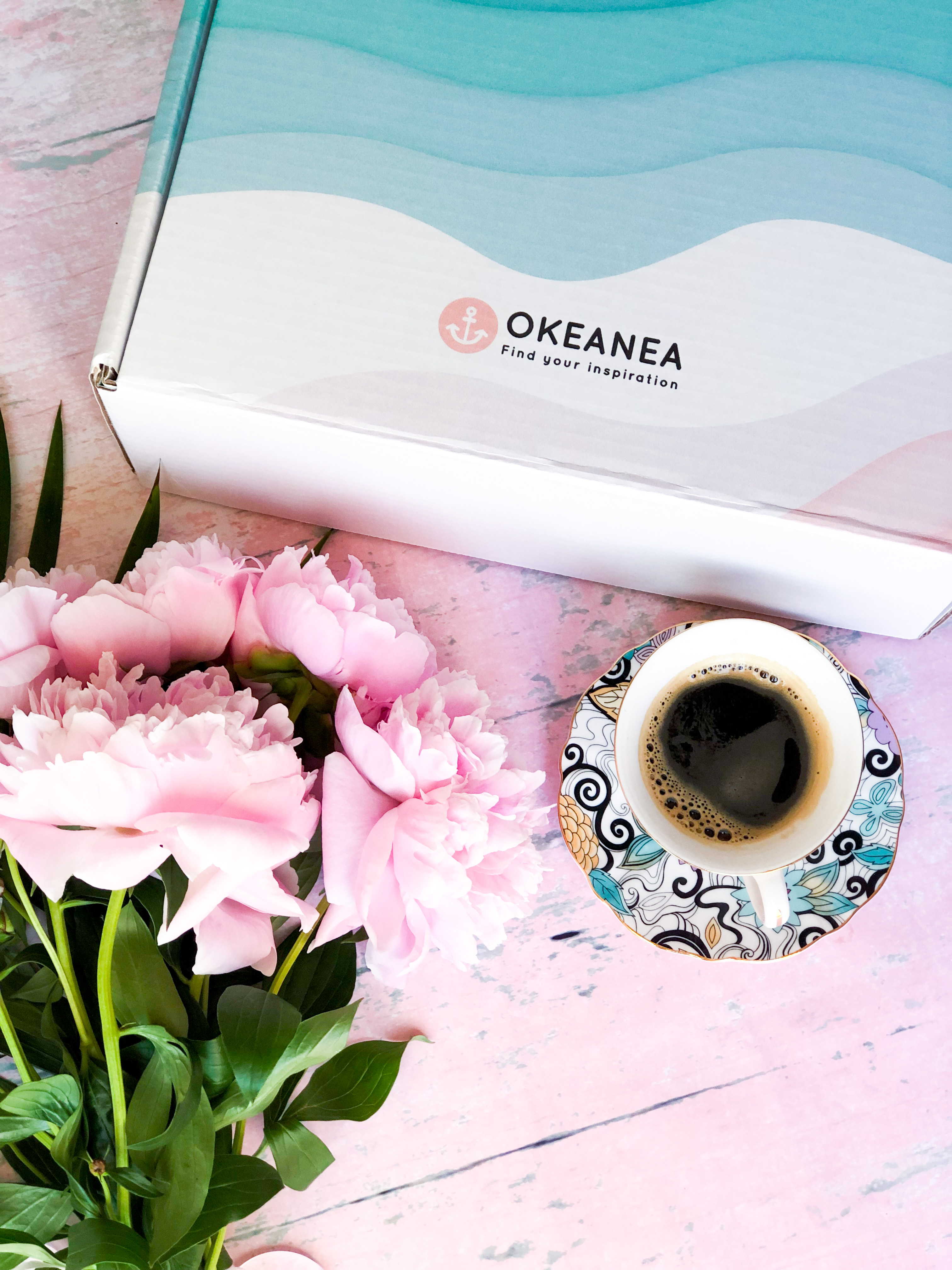 A book subscription box beautifully placed among flowers and a cup of coffee