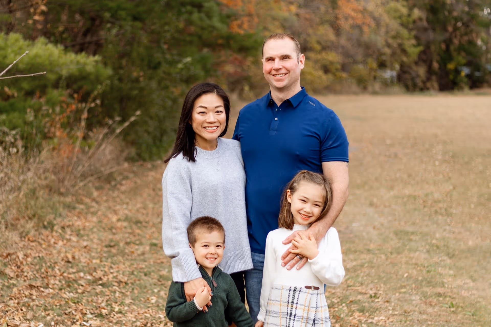 Chris Steward with his family posing in front of fall trees and leaves background