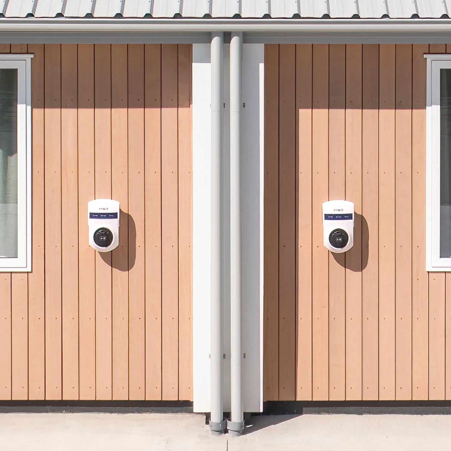 Two white electric vehicle charging stations mounted on the exterior of each villa