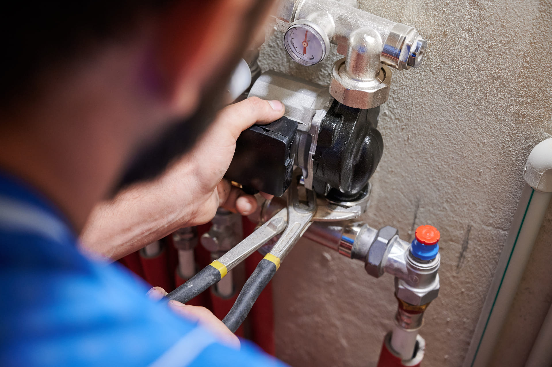Techniker bei der Wartung oder Reparatur einer Heizungsanlage mit Ventilen und Anschlüssen.