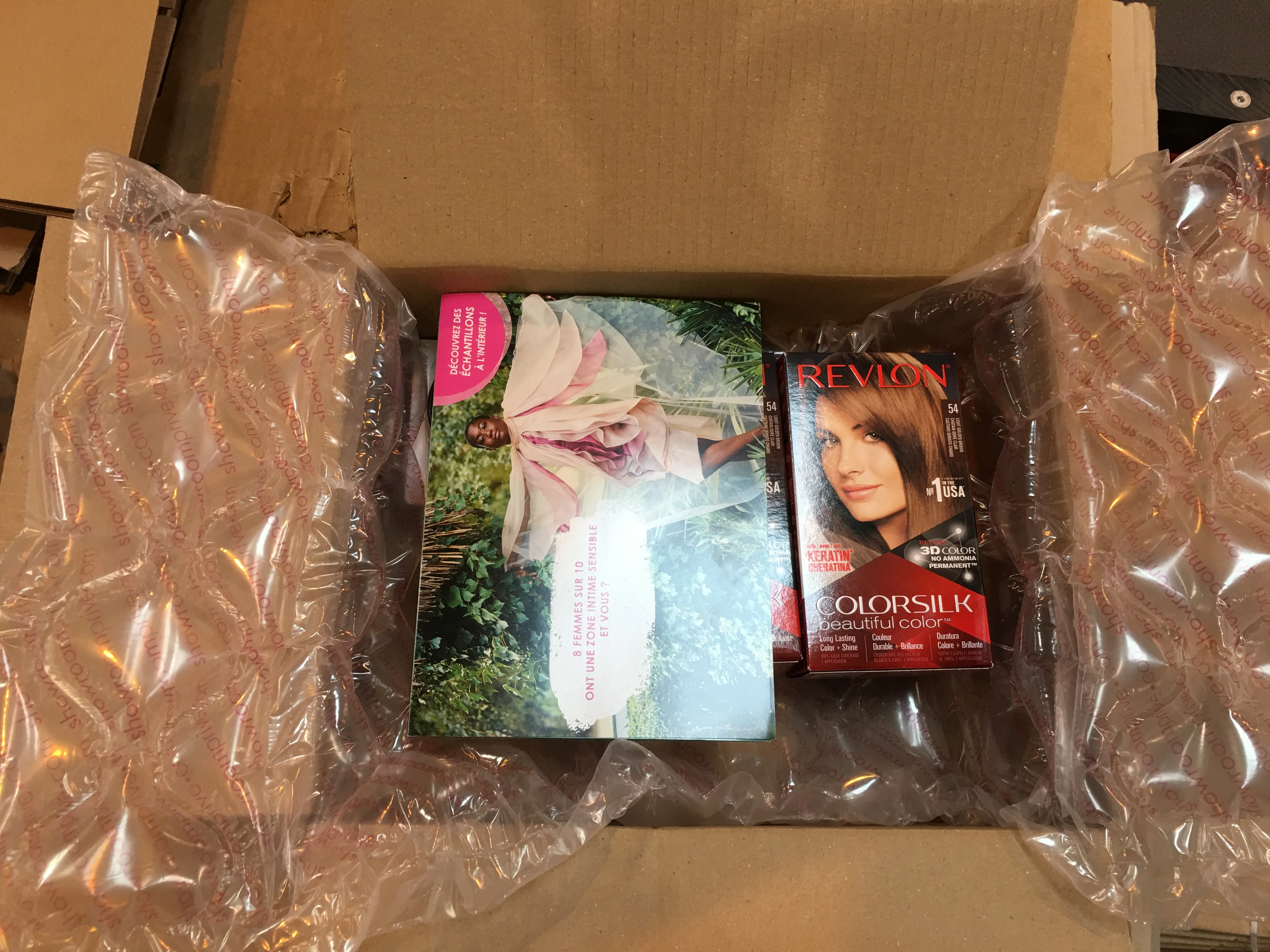 Boîte en carton ouverte contenant un emballage gonflable et une boîte de coloration de cheveux Revlon Colorsilk.