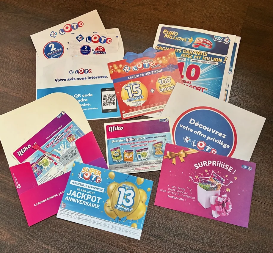 Plusieurs tickets et brochures de jeux de loterie FDJ, incluant Loto, EuroMillions, Super Loto et Illiko, posés sur une surface en bois.