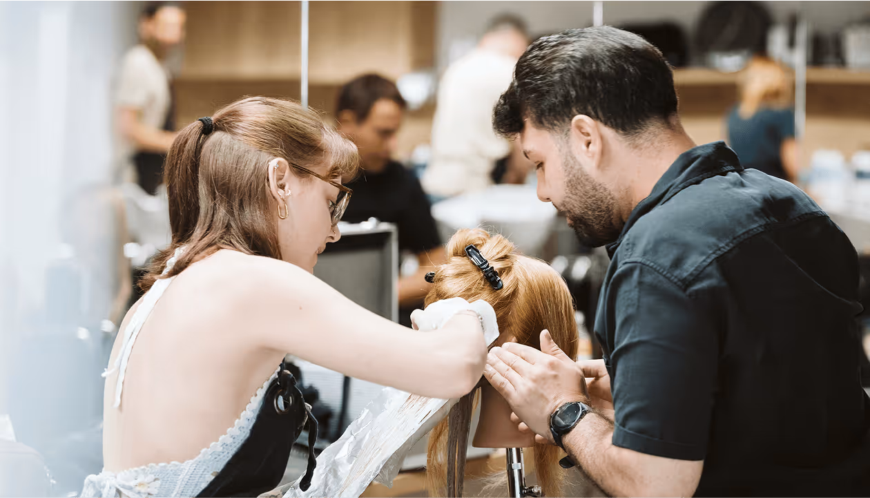 Friseure färben Haare an Puppe, fokussierte Arbeit in modernem Salon. Professioneller Umgang mit Blondtönen.