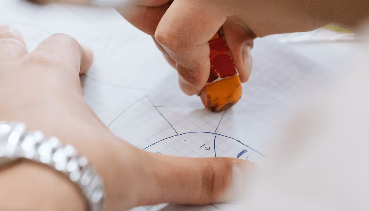 Hand zeichnet geometrische Formen auf Millimeterpapier mit Bleistift-Radiergummi; Detailaufnahme; Fokus auf Präzision.
