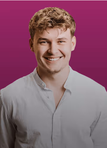 Mann mit lockigem Haar in weißem Hemd, lächelt vor lila Hintergrund.