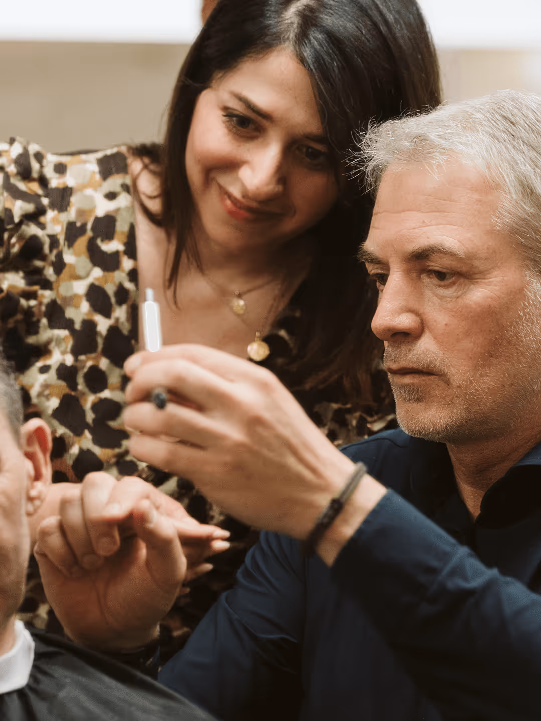 Friseur konzentriert sich aufs Haareschneiden, während Frau zusieht.
