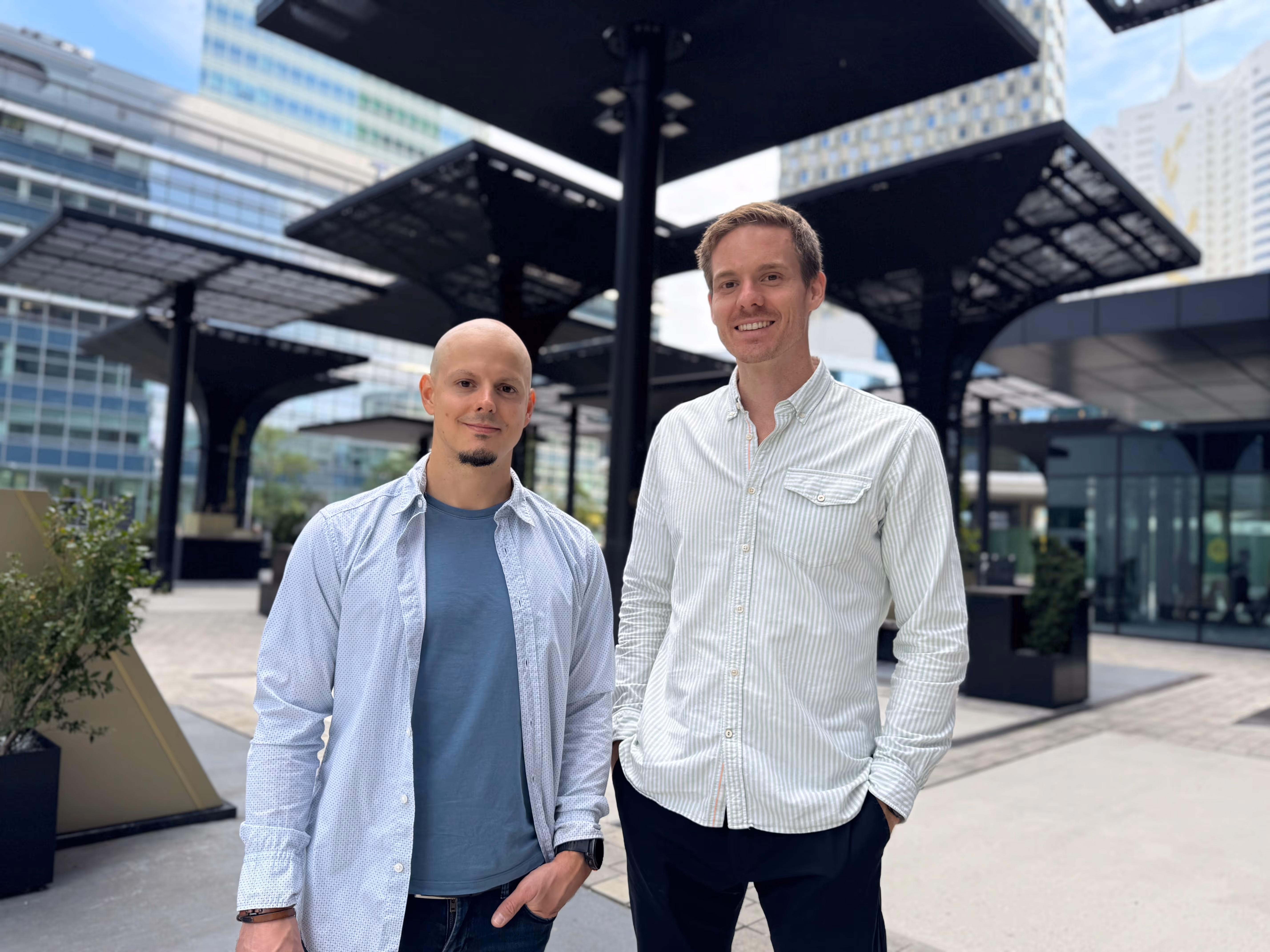 Two men in an urban office area with high-rise buildings.