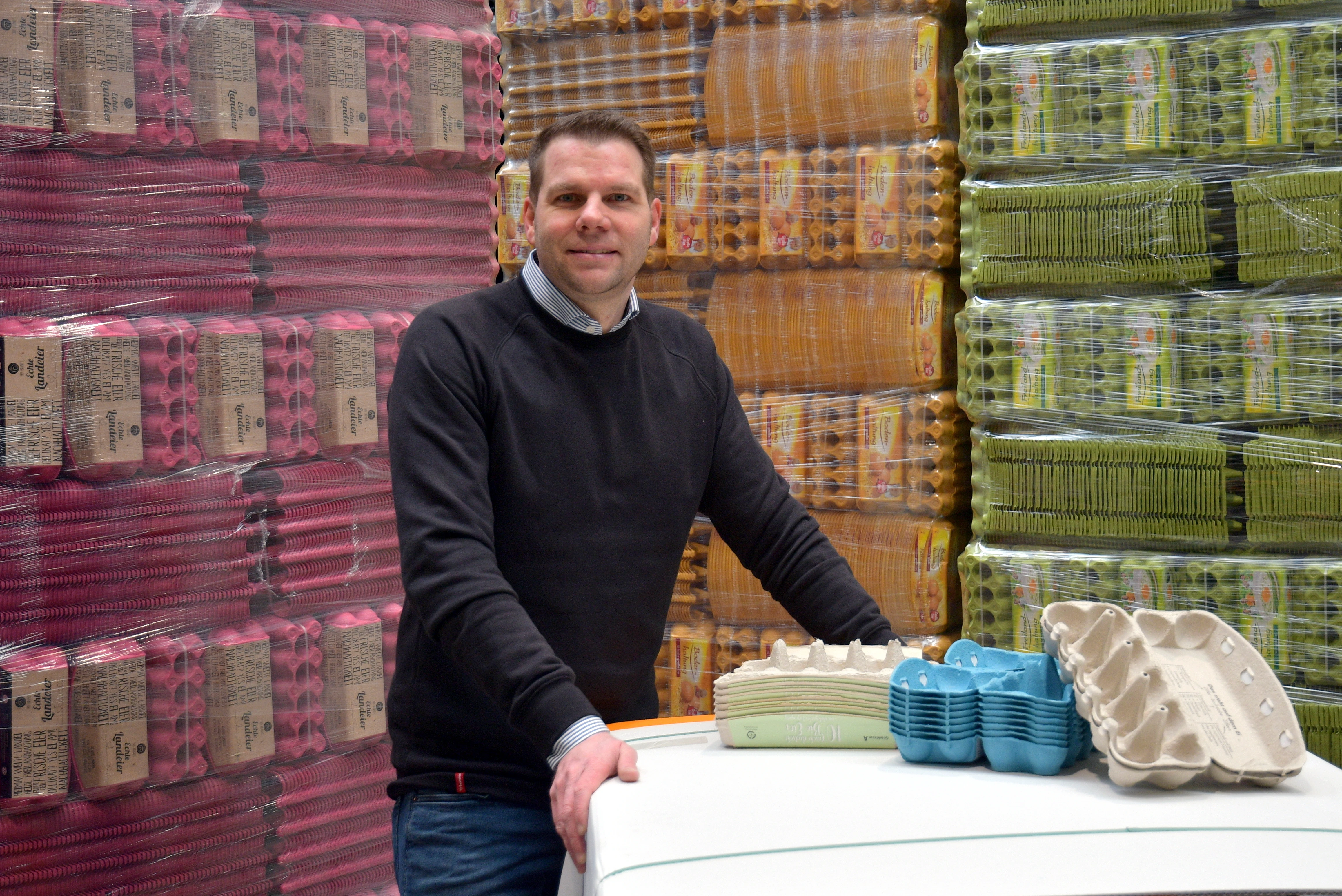 Person-steht-vor-vielen-bunten-Eierkartonagen