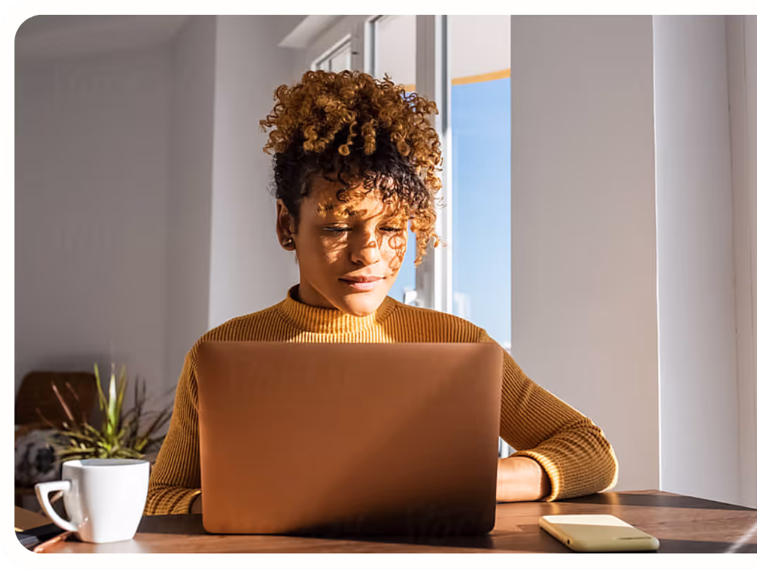Femme assise à un bureau, devant un ordinateur, près d'une fenêtre