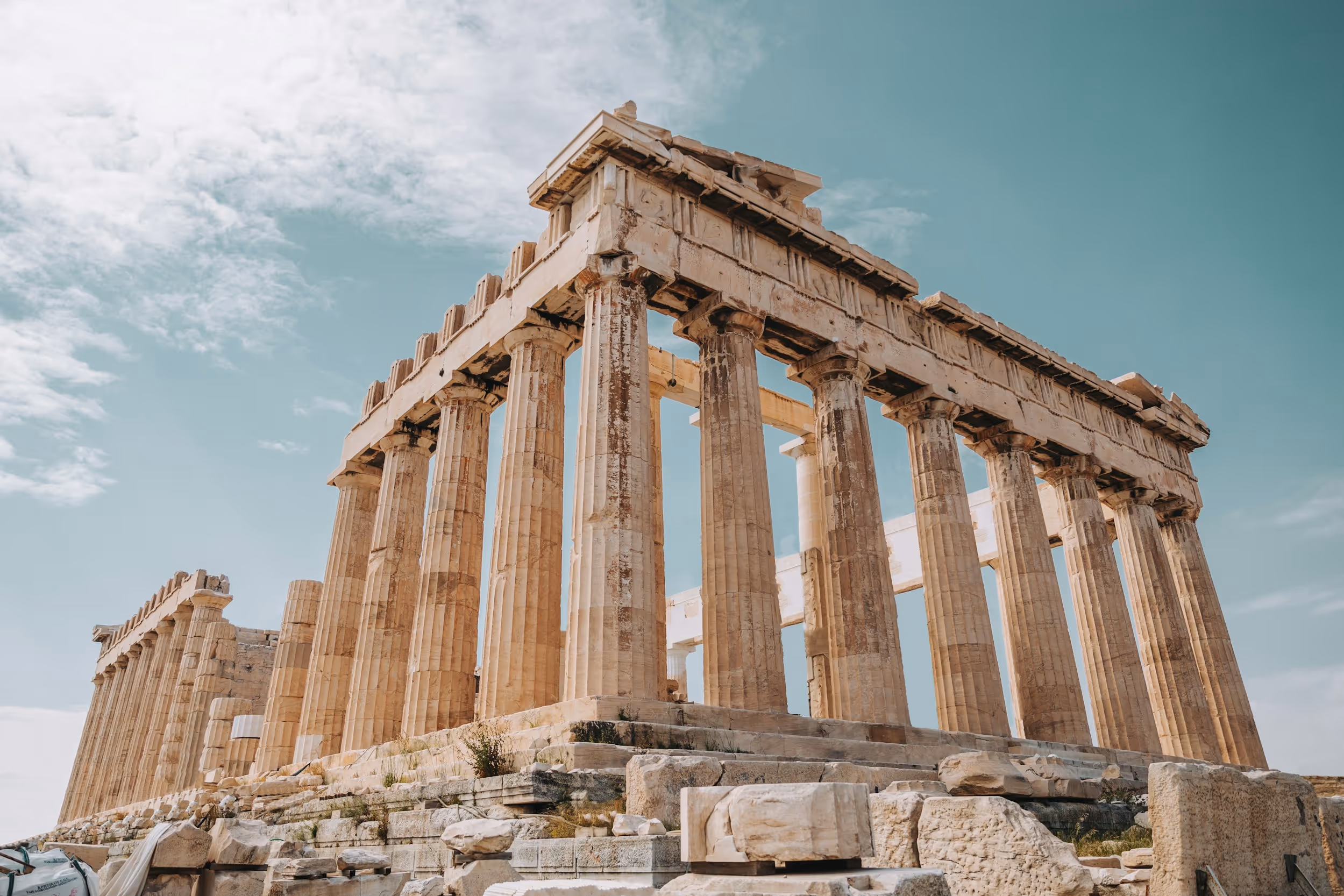 The Parthenon, an ancient temple with large stone columns under a partly cloudy sky.