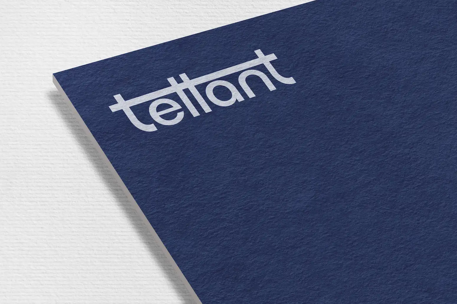 Close-up of a navy blue textured card with the word 'tellant' written in lowercase white letters and a horizontal line connecting the top of the first four letters.