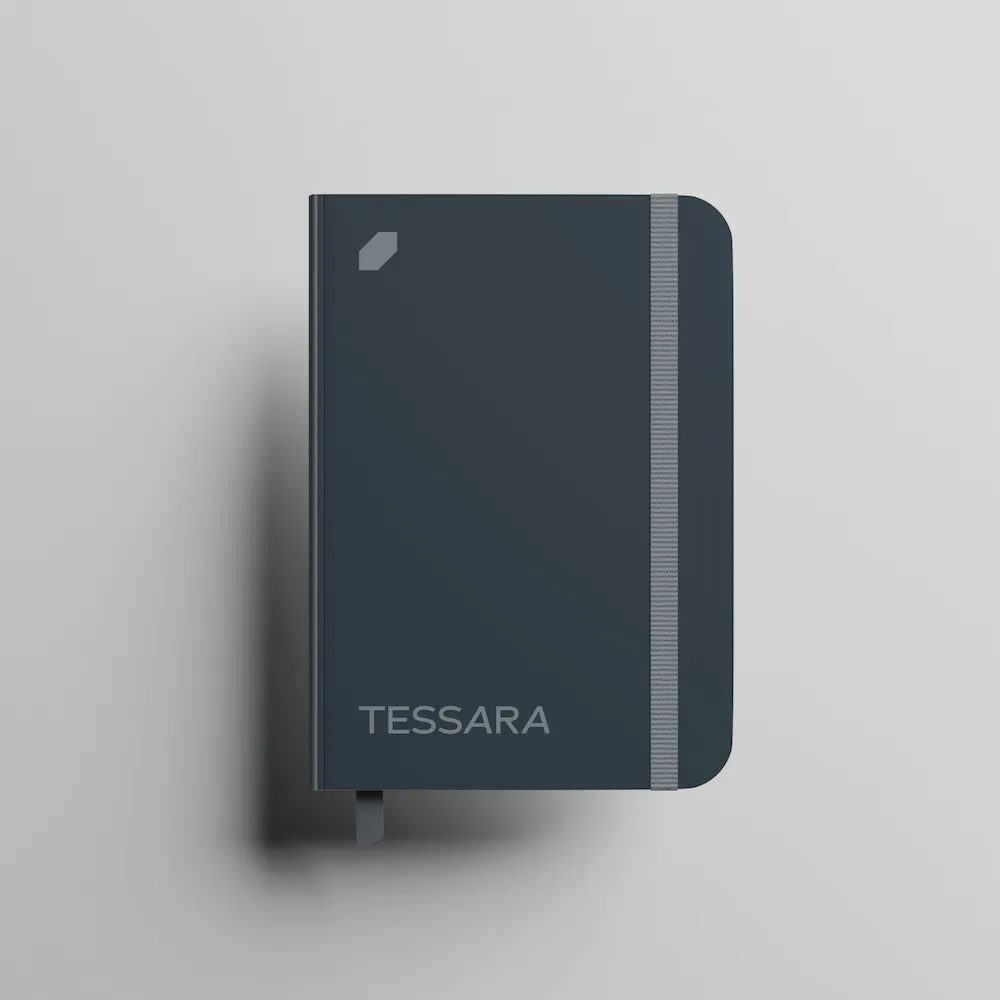 Closed dark blue notebook with a grey elastic band and the word TESSARA on the cover.