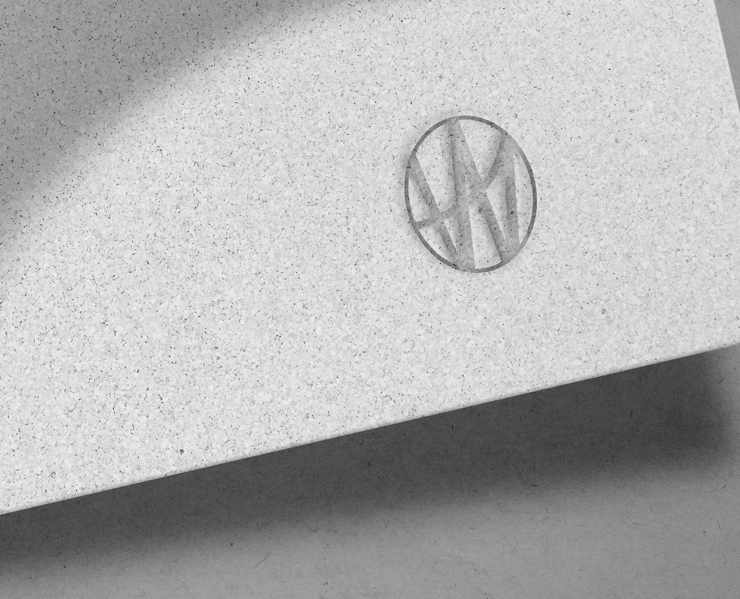 Close-up of a textured paper envelope with a circular embossed logo for Watkins Range featuring stylised initials.