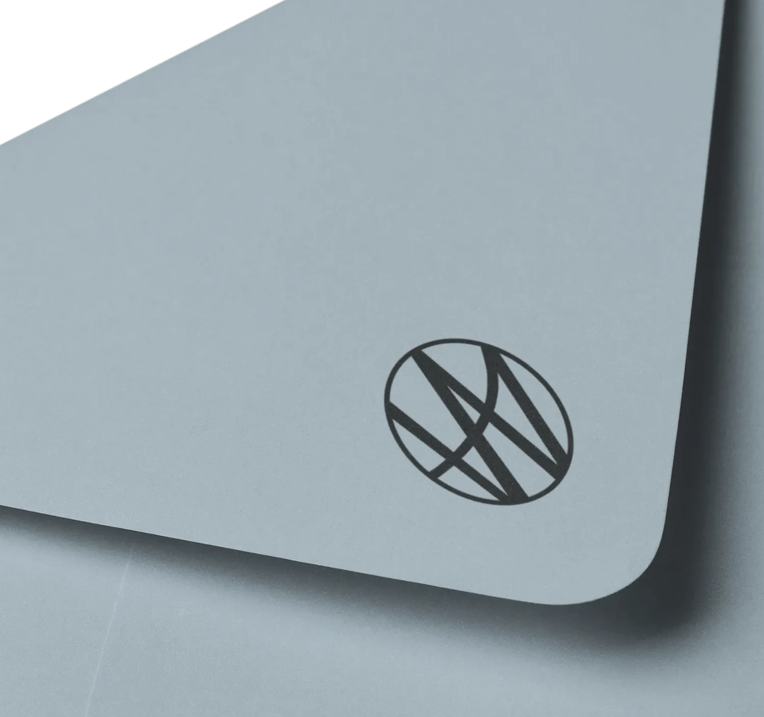 Close-up of a grey envelope corner with a round black geometric logo design for Watkins Range.