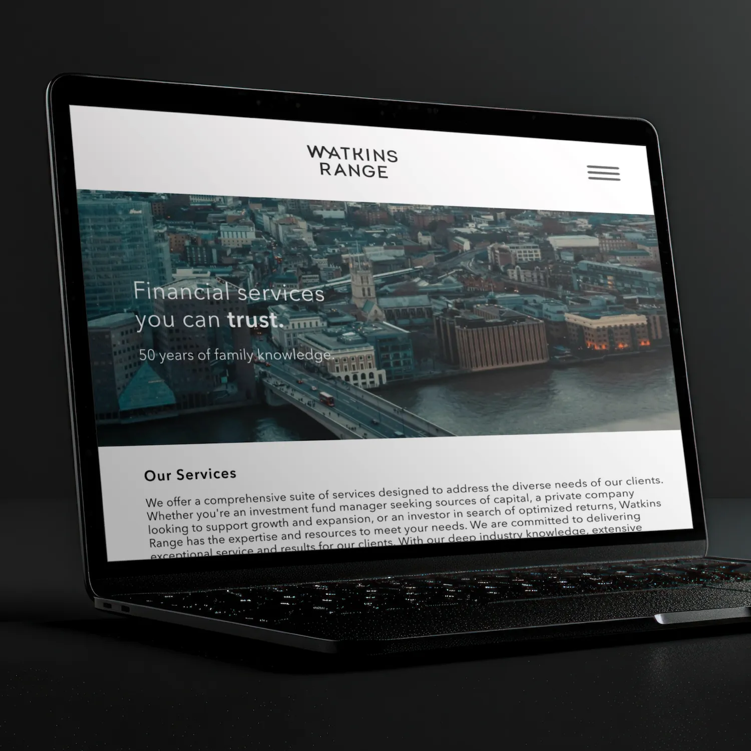 Laptop screen displaying Watkins Range financial services website with cityscape and river background.