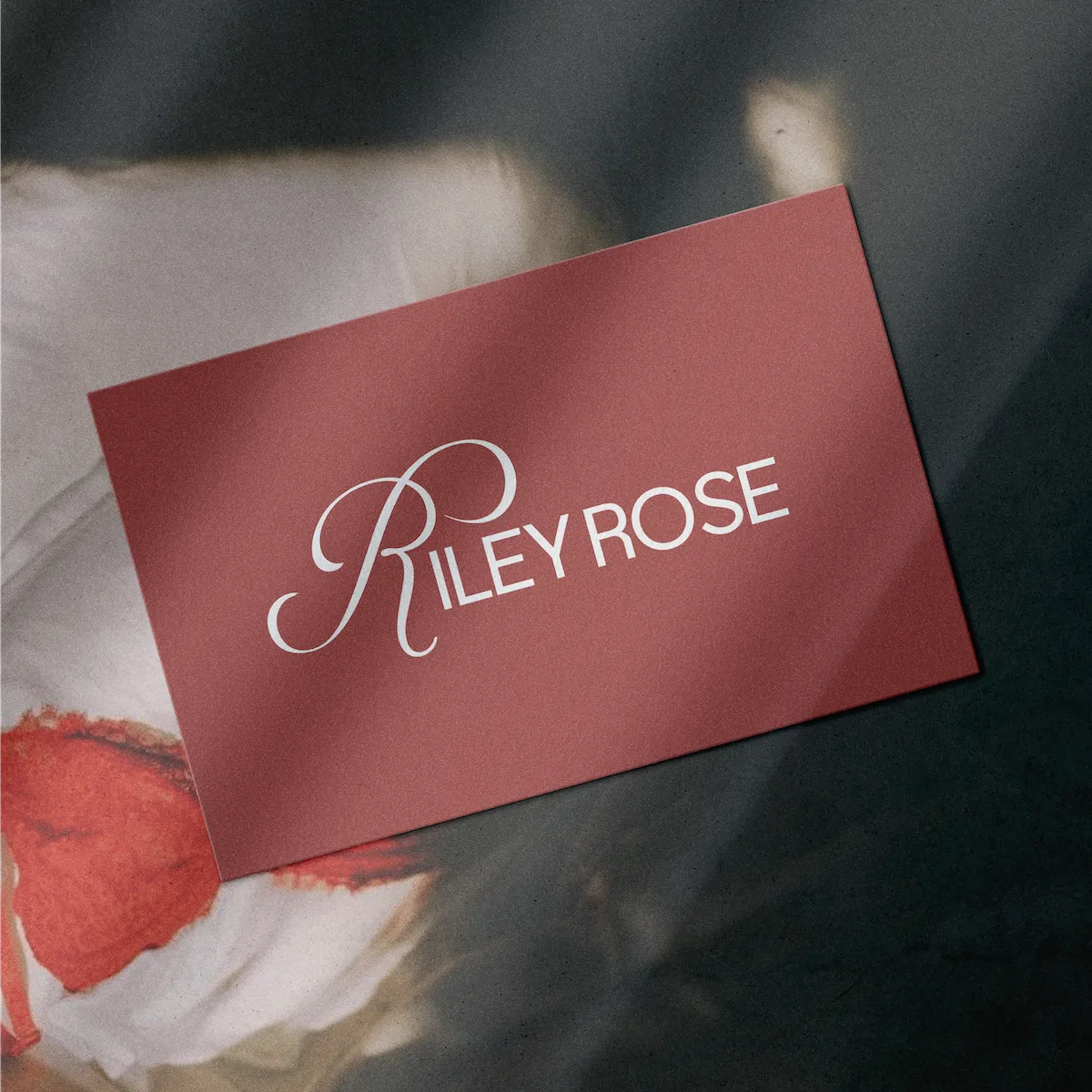 Red business card with the white text 'Riley Rose' displayed diagonally.