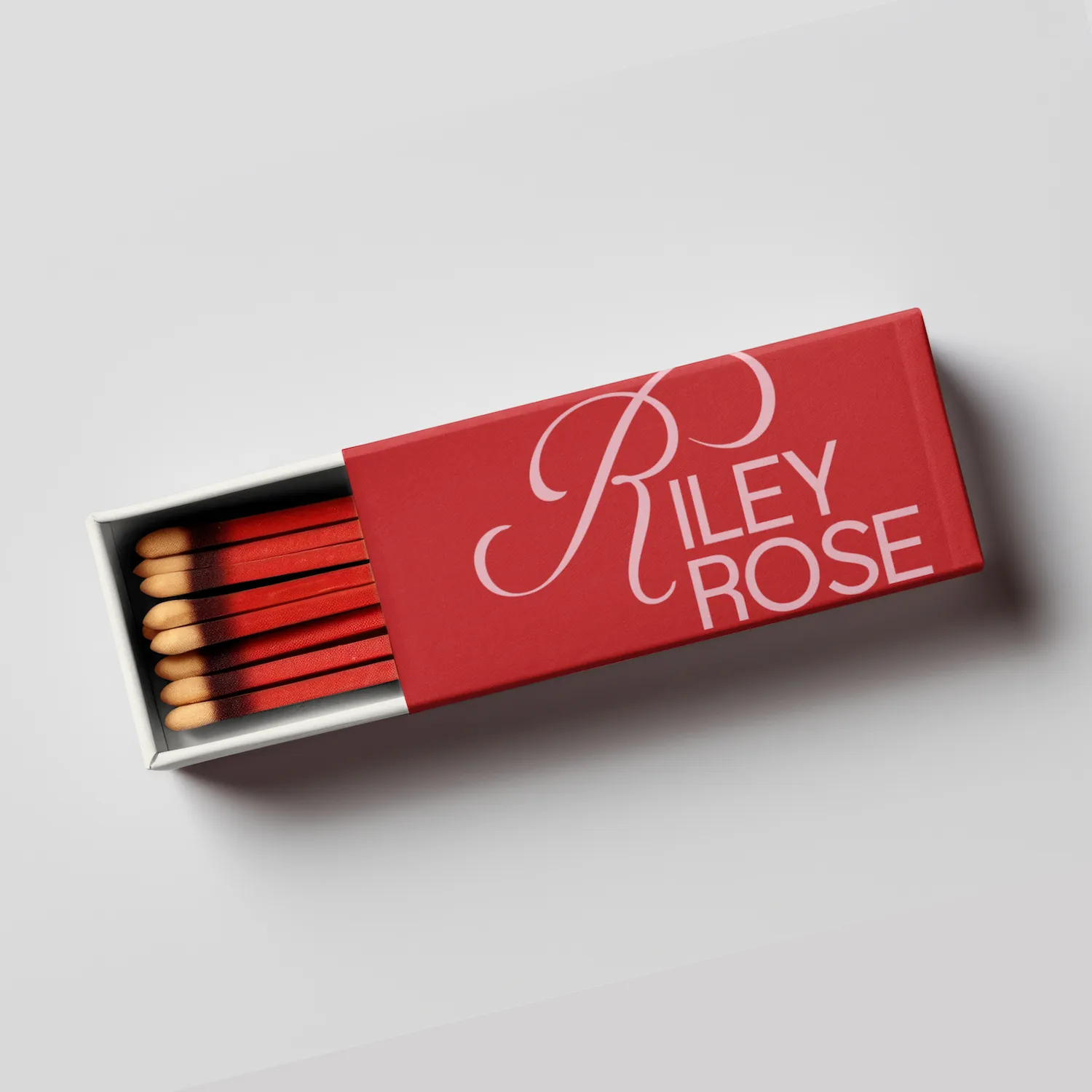 Opened matchbox with red matches and a red sleeve labeled Riley Rose.
