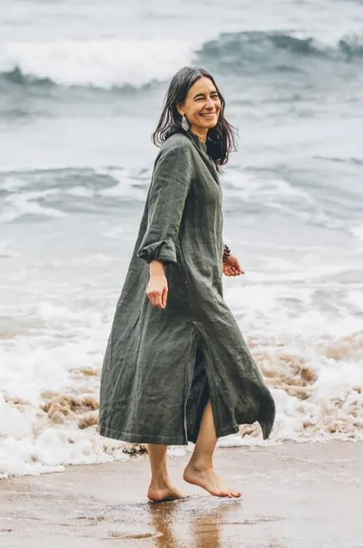 Smiling woman walking barefoot on the beach.