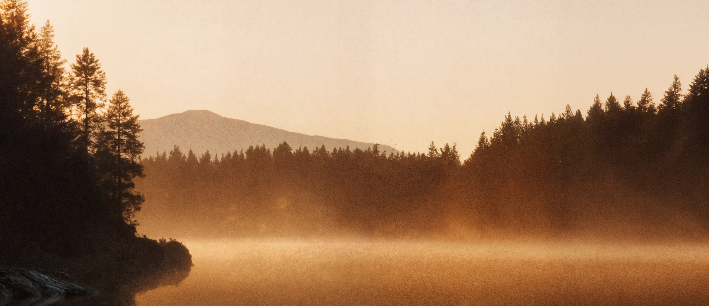 Sunrise mist over forested lake