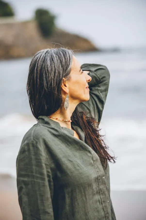 Woman standing by the sea, looking peaceful.