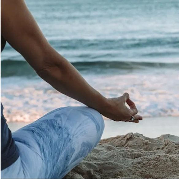 Person meditating on the beach.