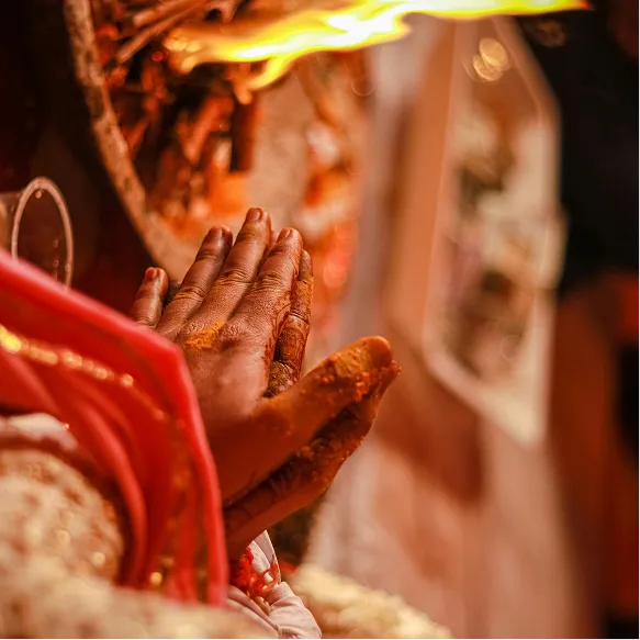 Hands in prayer near sacred fire.