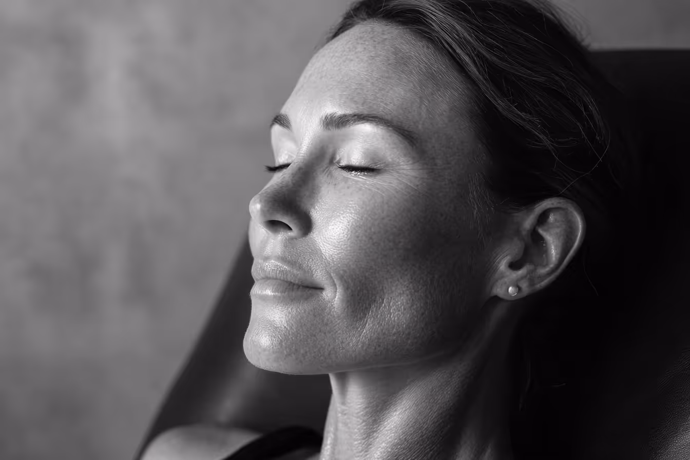 Close-up of a woman with closed eyes and a serene expression, highlighting her smooth skin texture.