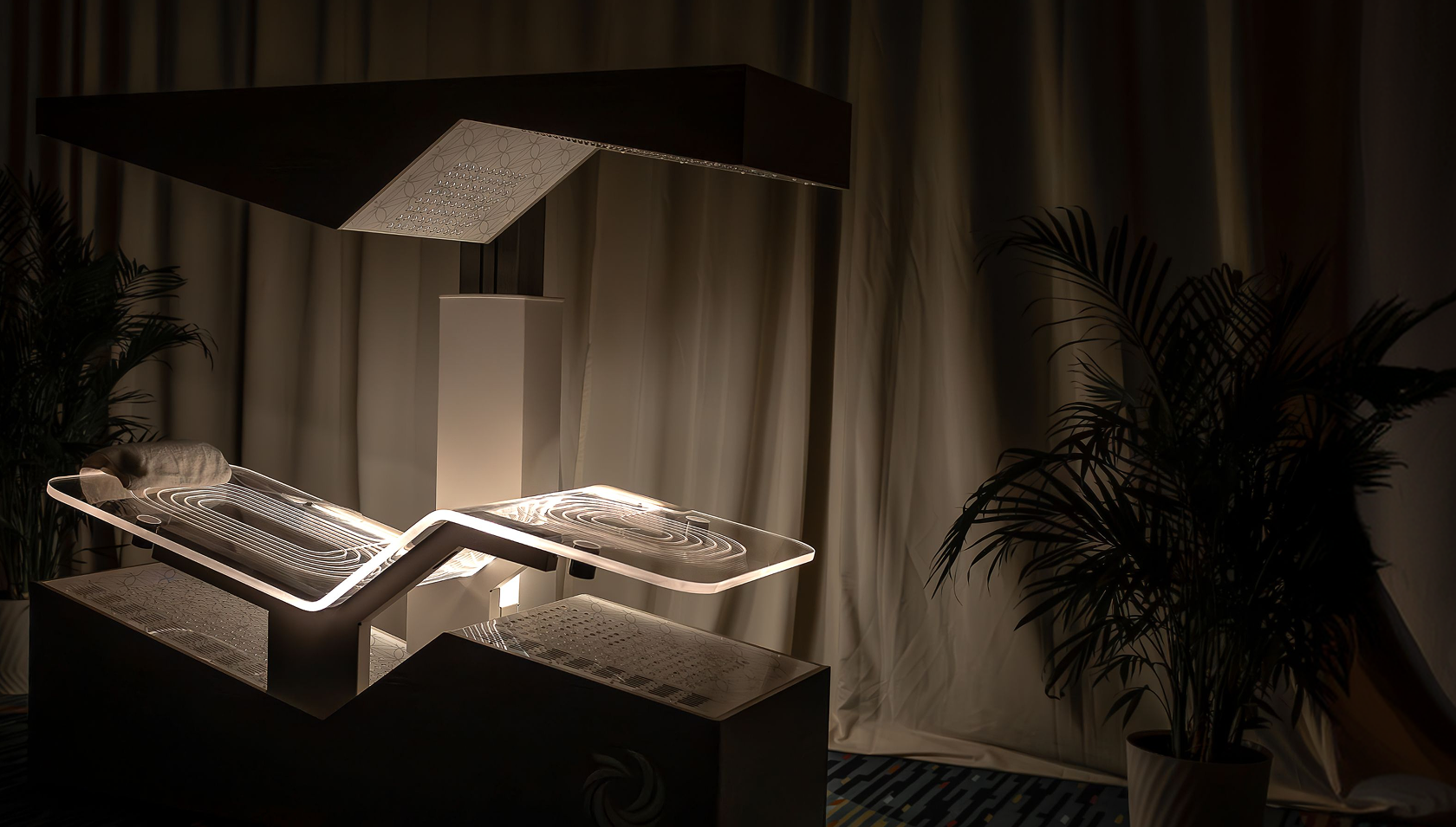 The Ammortal Chamber illuminated beneath its overhead light panel in a calm, plant-filled room