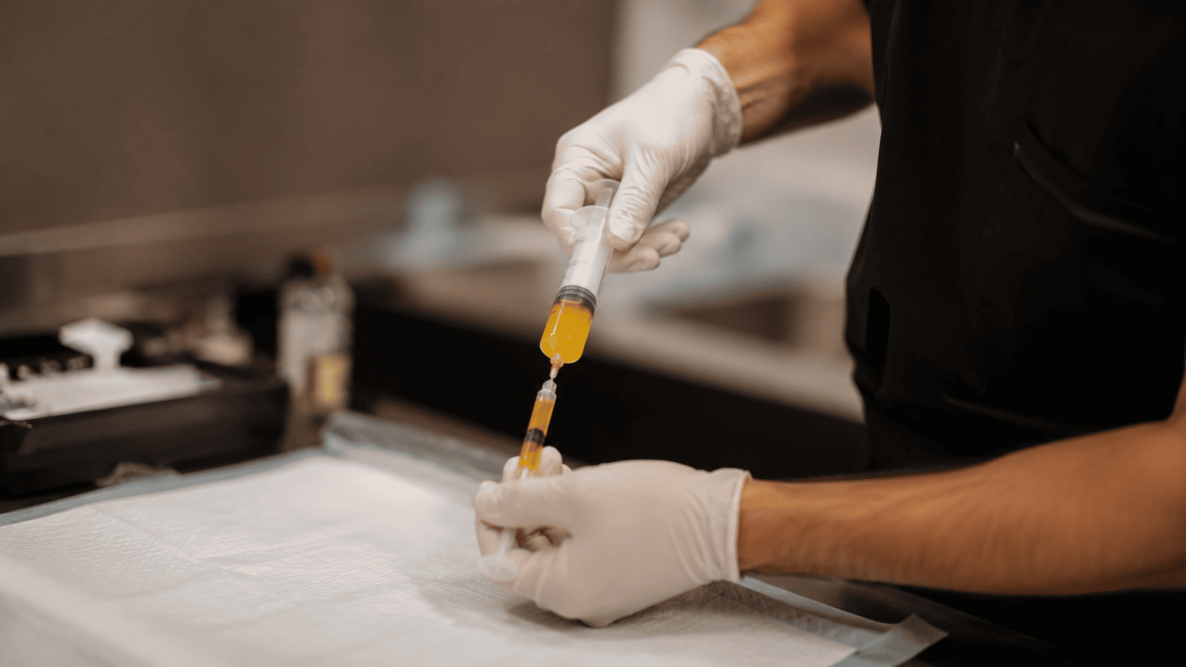 Healthcare professional preparing a platelet-rich plasma (PRP) injection by drawing golden plasma into a syringe in a sterile clinical setting.