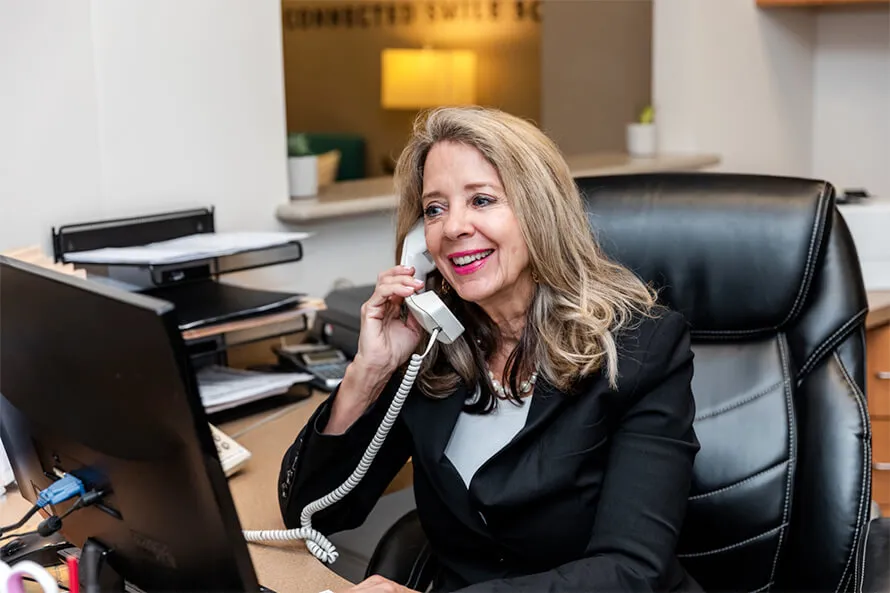 Connected Smile Solutions team member talking on the phone and smiling.